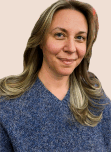 A female professor in a blue sweater smiles for a photo.