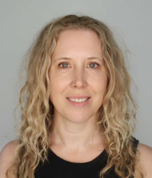 Woman with curly blonde hair smiles for a headshot.