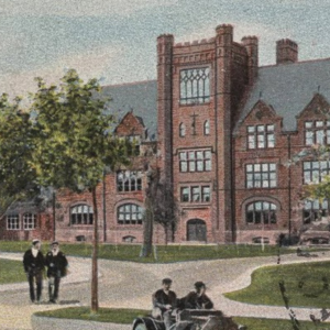 Individuals in historical clothing walk or drive outside a brick building.