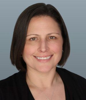 Woman with short dark hair smiles for a photo.