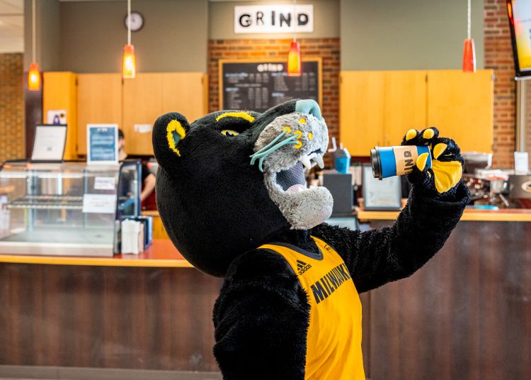 Pounce drinks a cup of coffee at the Grind Coffee Shop in the Golda Meir Library.