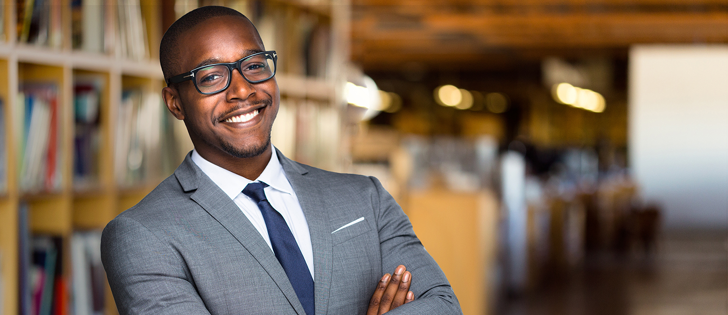 Black man in a suit smiling in a library