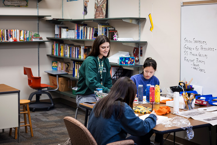 UWM student working on an art project with middle schoolers.