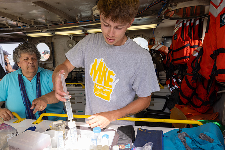 A Student working with water samples with his mentor inside the Neeskay.