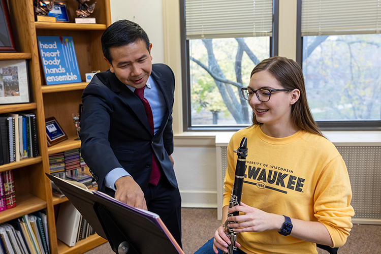 Kate, a UWM student practicing clarinet and receiving advice from her mentor.