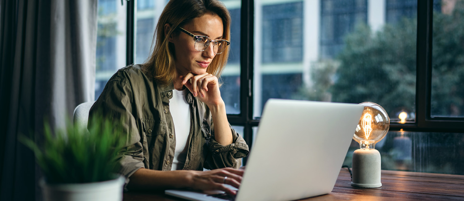 A young professional working on a laptop in an office setting.
