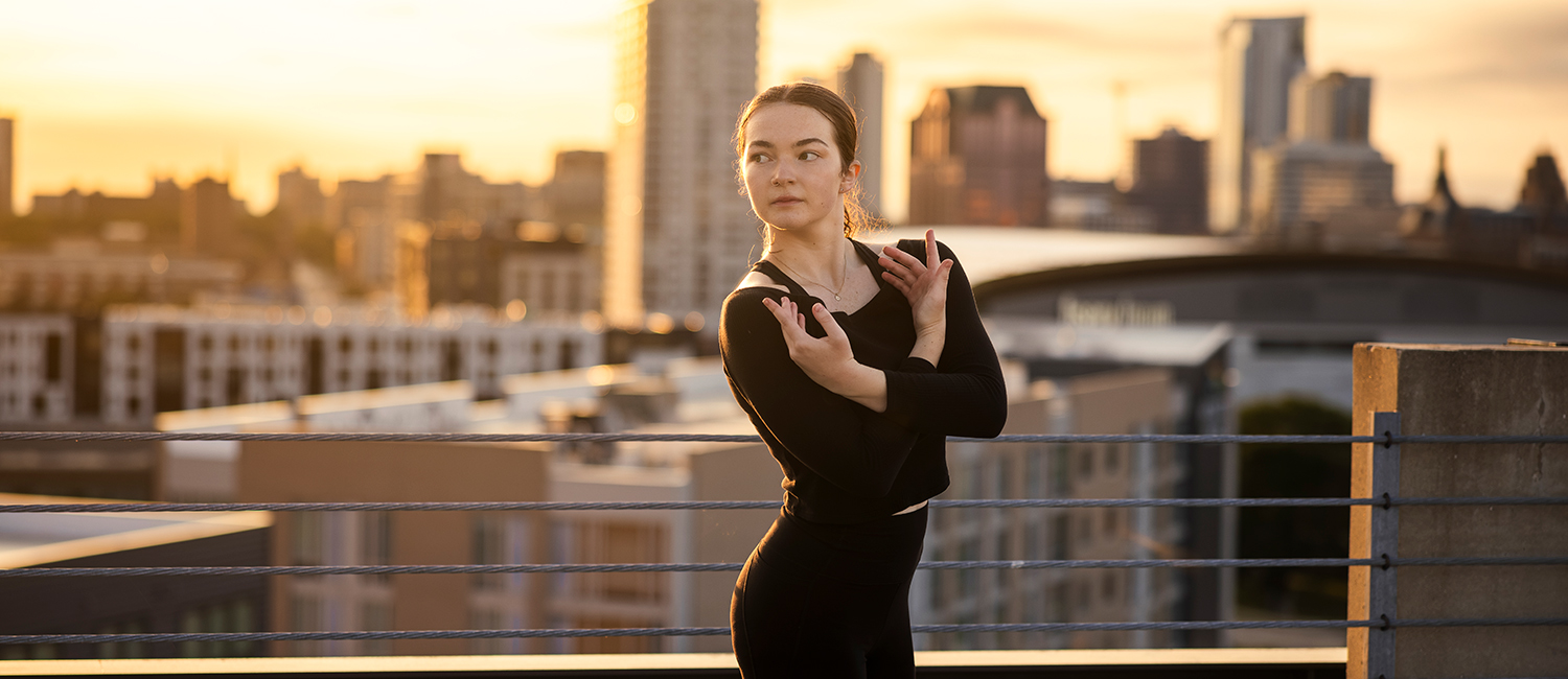 A UWM dance student practicing on a rooftop with the City of Milwaukee in the background.