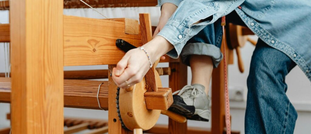 Person operating a traditional wooden weaving loom.