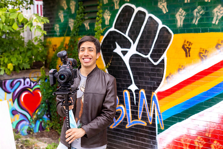 Videographer holding a camera poses for picture