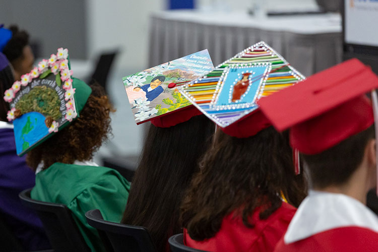 Students in graduation caps and gowns listen to a talk
