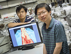 Yaoyi Li (foreground) and Mingxing Chen, UWM physics postdoctoral researchers, display an image of a ribbon of graphene 1 nanometer wide. In the image, achieved with a scanning-tunneling microscope, atoms are visible as “bumps.”