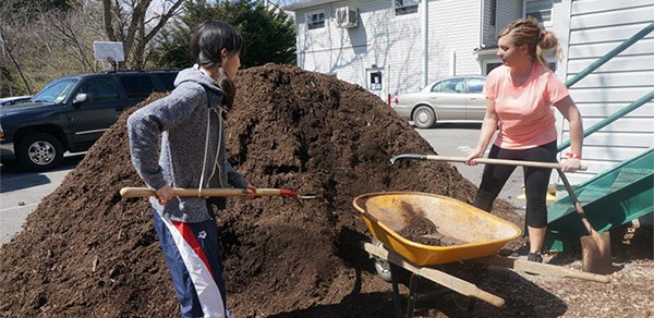 UWM education major Yukako and human resources management major Brooke Larson work together to shovel mulch at the Steadfast House, a women and children’s shelter.