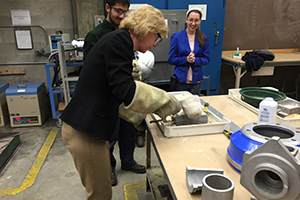Students help U.S. Sen. Tammy Baldwin pour a casting during a tour of the Center for Advanced Materials Manufacturing at the College of Engineering & Applied Science. (UWM Photo)