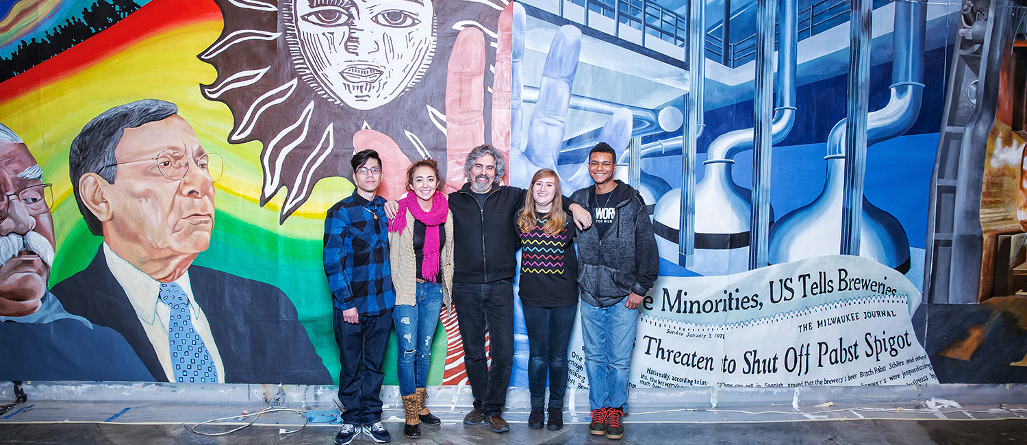 Raoul Deal poses with his students in front of the mural.