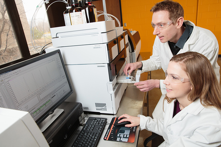 Alexander “Leggy” Arnold, associate professor of chemistry, guides graduate student Margaret Guthrie in analyzing a drug compound with a mass spectrometer. (Photo by Peter Jakubowski)