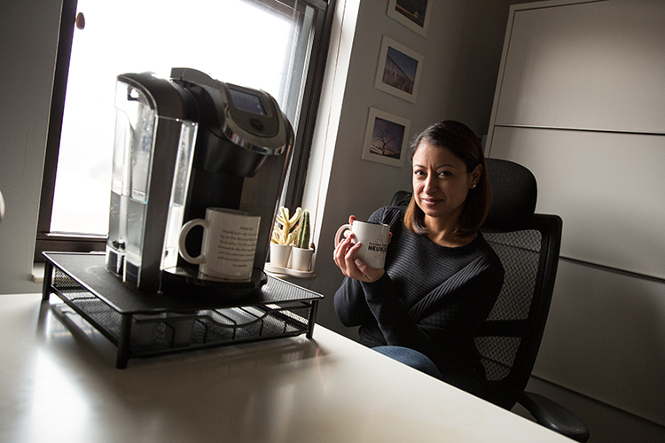Ira Driscoll sits at her desk drinking coffee.