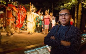 James Flores stands in front of a diorama depicting American Indian life.