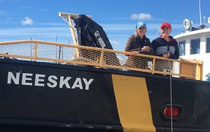 Two women stand at the railing of the research ship Neeskay.