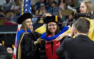 Adviser places the hood on graduate
