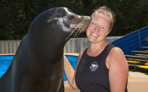 A sea lion nudges a woman's face with his nose.