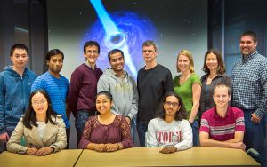 Physicists pose for a photo in front of a space image.