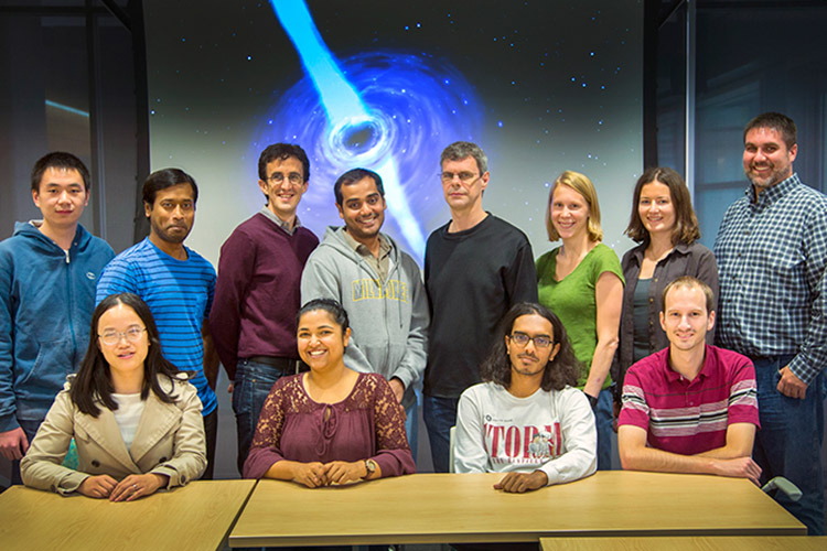 Physicists pose for a photo in front of a space image.