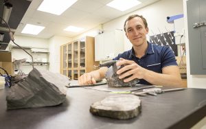 Erik Gulbranson sits at a table in a lab with samples of rock.