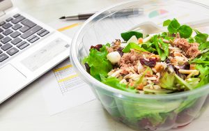 Bowl of salad next to a laptop