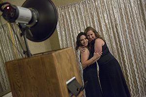 Two students hug while posing for a photo.