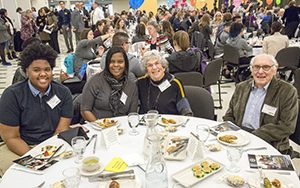 Four people sit at a cloth covered table.
