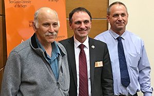 Three men pose for a photo.