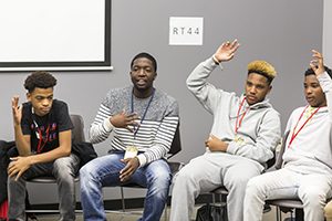 Several students raise their hands during a discussion.