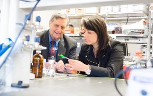 David Rice and Marcia Silva sit in a lab looking at a water sensor.