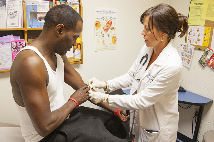 a nurse bandages a patient's arm after drawing blood