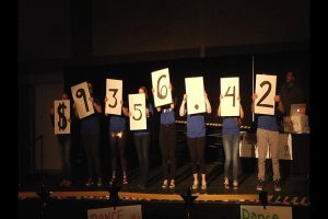 Students hold up cards showing the dance event raised $9,356.