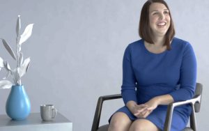 Molly Poppie sits in a chair looking off to the right.