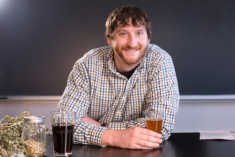Grad student Josh Driscoll holds a glass of beer.