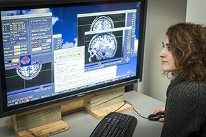 A woman looks at images of brains on a computer screen.