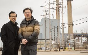 Wei Wei and Lingfeng Wang stand on a street in front of some power lines.