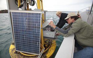 Two men examine research equipment on a boat on Lake Michigan.
