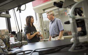 A student and teacher stand in a lab.