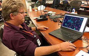 A man sits at a desk working on a laptop computer.