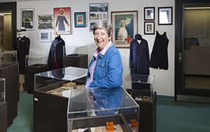 Laurie Glass leans against a display case in the nursing museum.