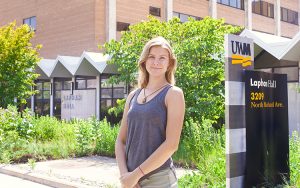 A student stands in front of a building at UWM.