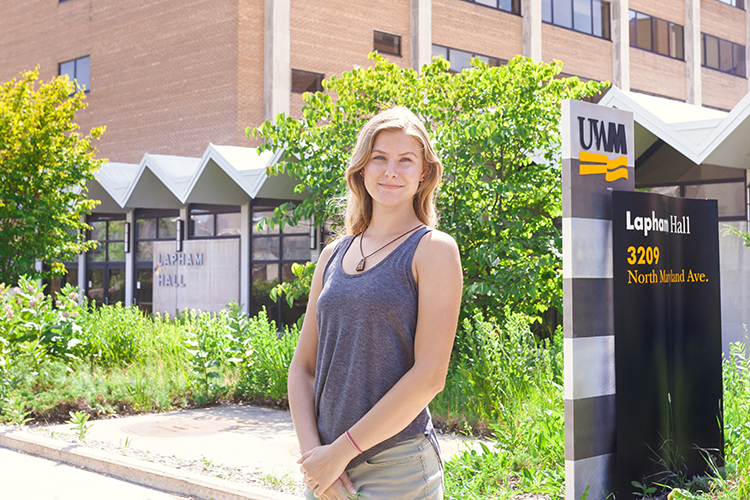 A student stands in front of a building at UWM.