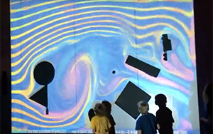 Children stand at a wall as a projection shows colorful lines depicting how a fluid would move.