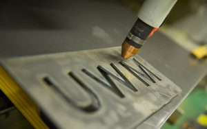 A piece of metal is carved with the initials UWM.