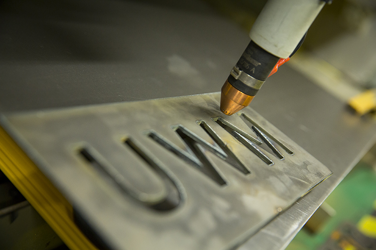 A piece of metal is carved with the initials UWM.