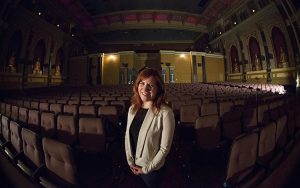 A woman stands amid rows of theater seats.