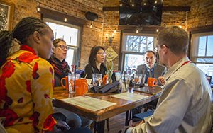 A group of people sit around a table and talk.